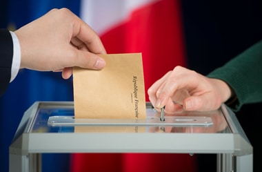 Photo d'une personne déposant son vote dans une urne