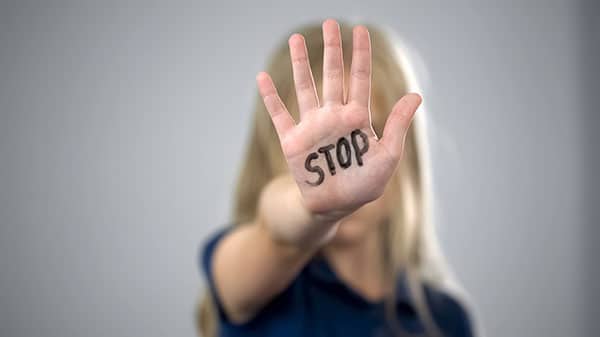 Femme qui montre la paume de sa main avec le mot "Stop" écrit