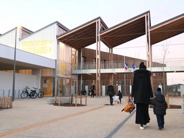 Femme qui marche avec son enfant devant une école