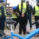 Groupe de personnes avec des gilets jaune devant un vélo bleu