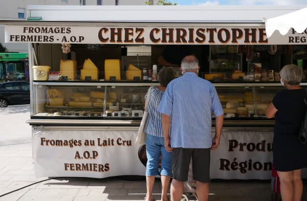 Groupe de personnes commandant au fromager du marché de Juvignac