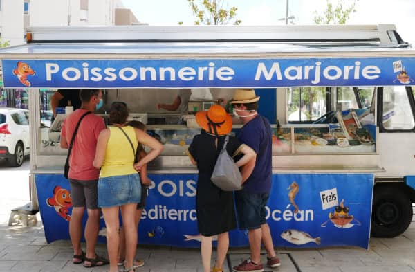 Groupe de personnes commandant à la poissonnerie du marché de Juvignac