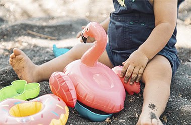 bébé sur la plage avec bouee flamant rose